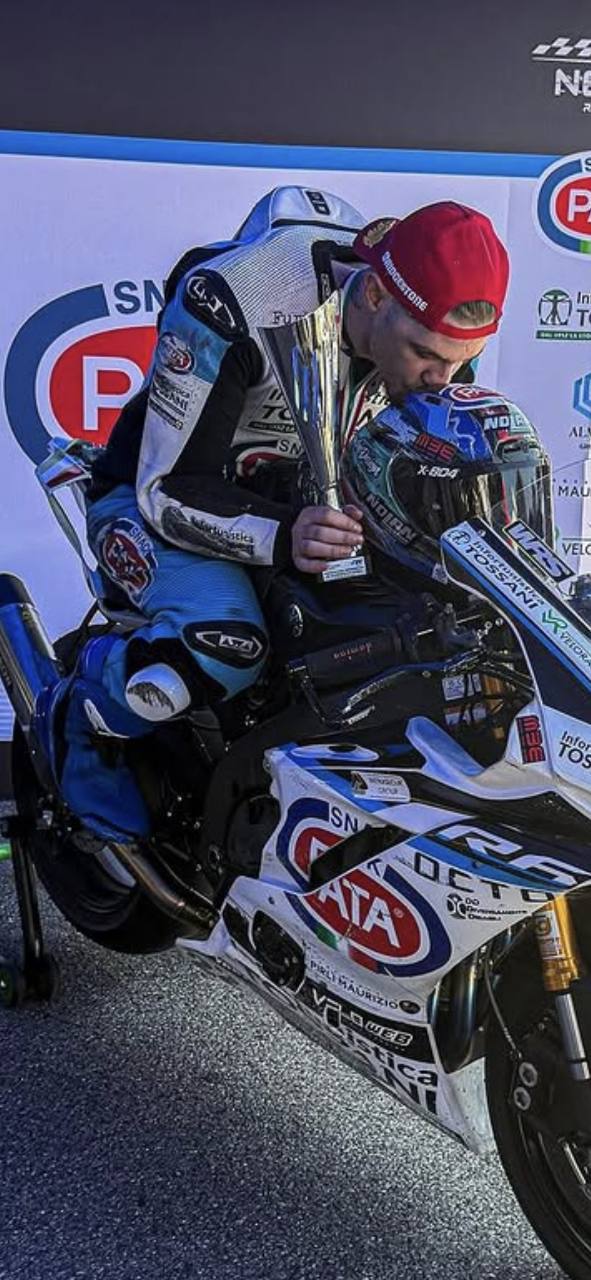 Omar con un trofeo accanto alla sua moto e al casco